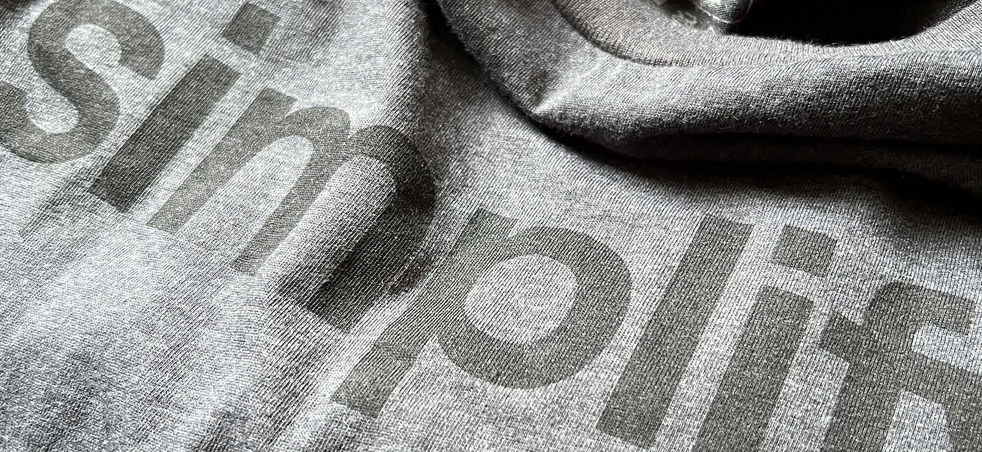 a closeup of a gray tee that says simplify