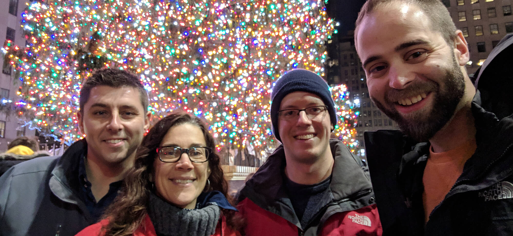 the Adjacent team taking a selfie in front of the Rockefeller Center tree