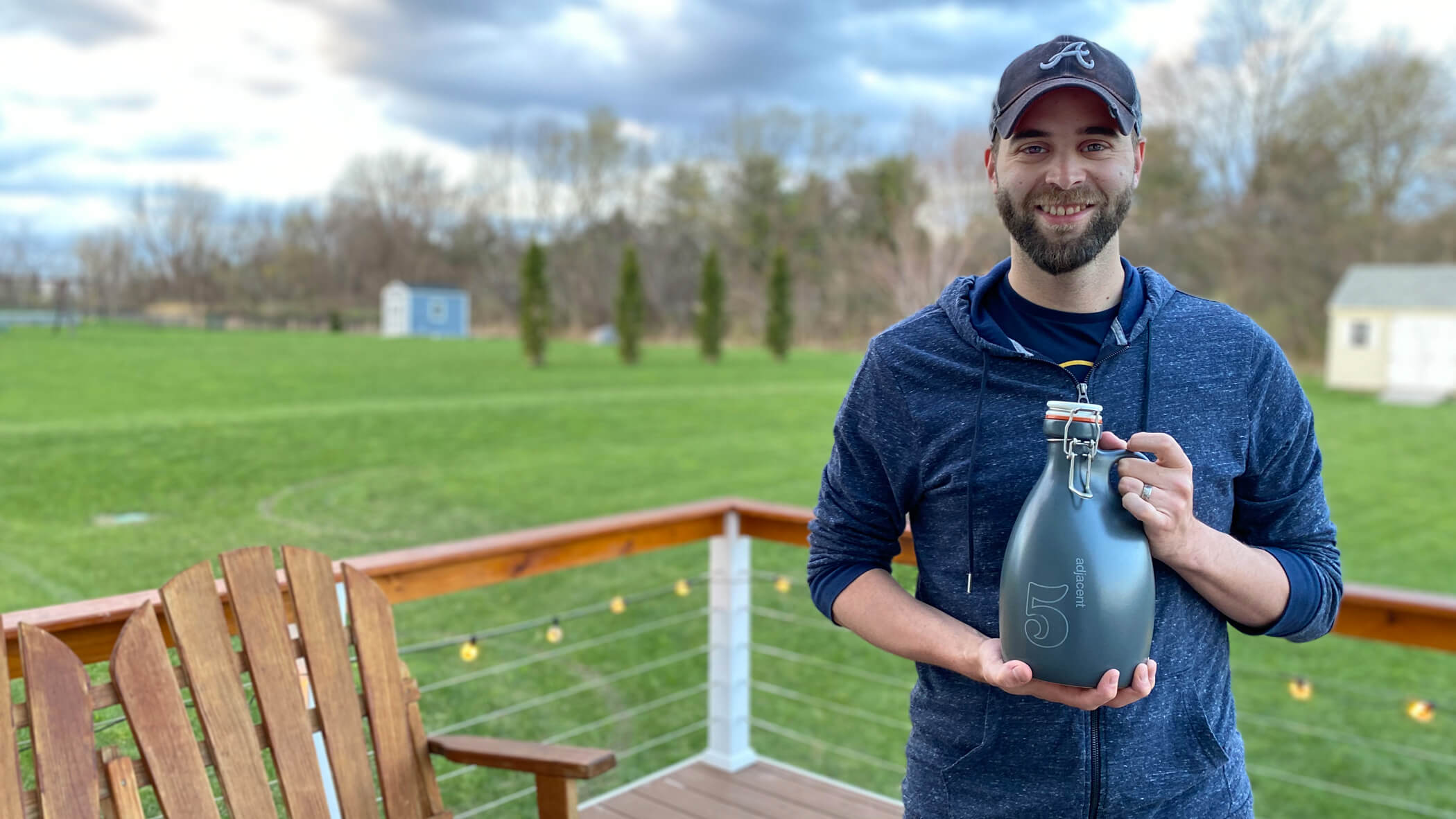 Dan standing on his deck holding a customized growler