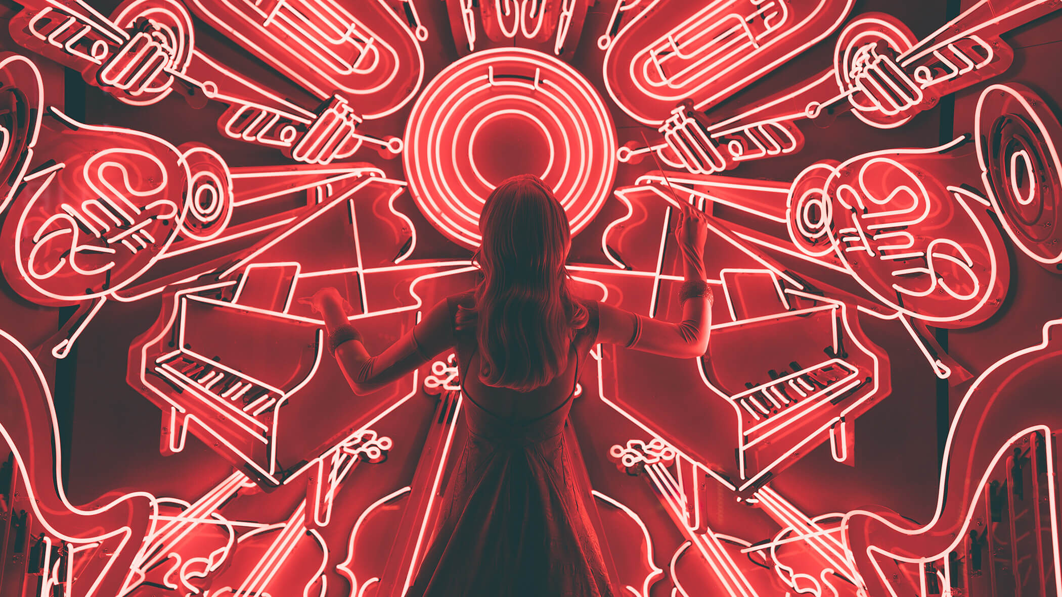 a woman standing in front of neon instruments as if to play the role of a conductor