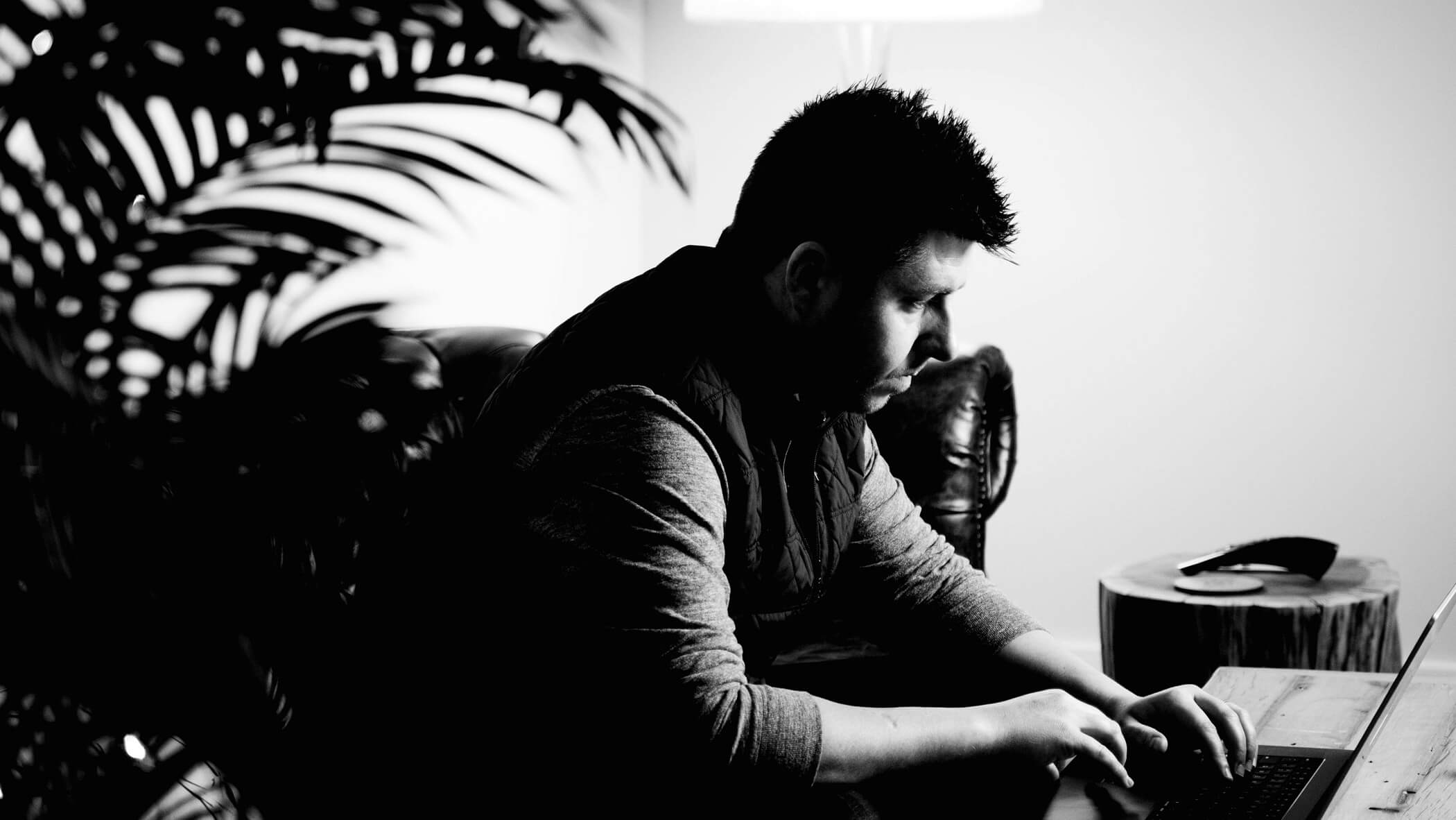 nate sitting on our studio sofa and using his laptop at the coffee table