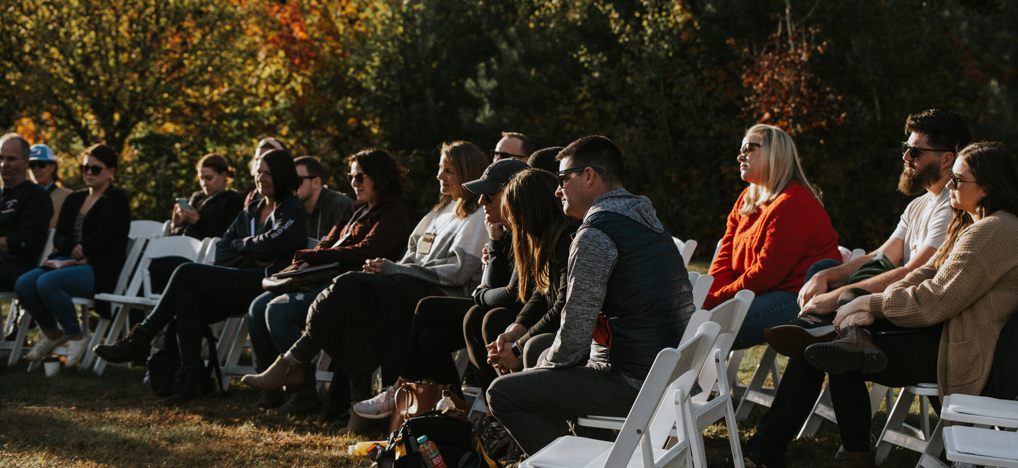 conference attendees seated in area by the pond in golden hour sunlight with foliage