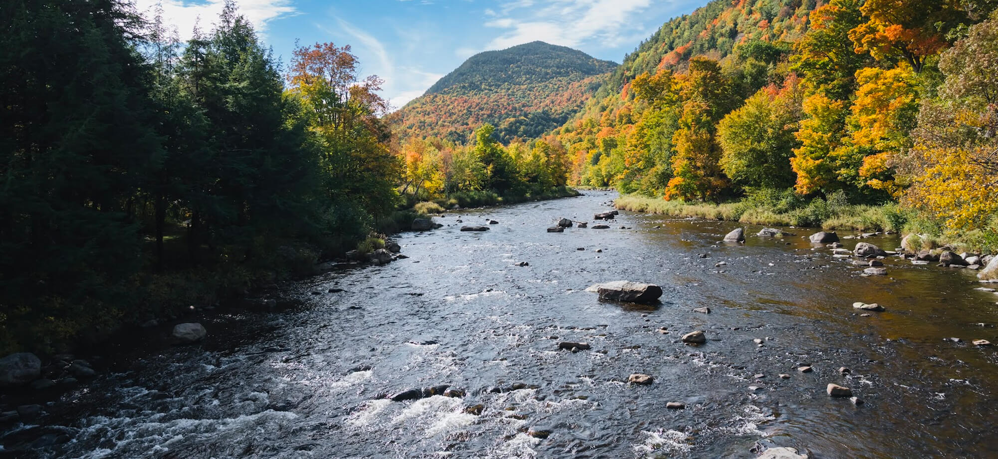 ADK Mountains with fal foliage and river in the foreground