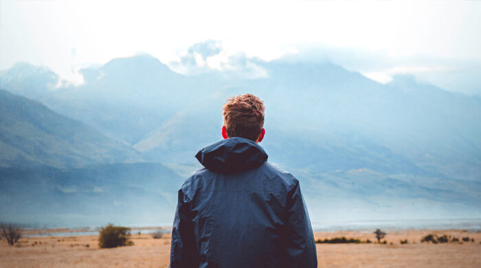 a man staring out at mountains in the distance